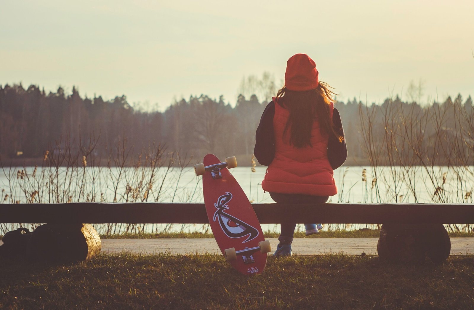 woman sitting on bench with longboard